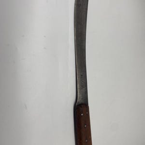 May include: A long, curved, silver blade with a wooden handle. The handle has a pattern of small, round holes. The blade is marked with the text "W.R. CASE & SONS BRANFORD, CT."