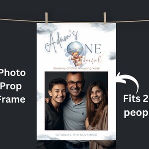 Puede incluir: Un accesorio de cabina de fotos azul y blanco con un diseño de globo aerostático y osito de peluche. El texto "Adam's One derful! Journey of One Amazing Year!" está impreso en el accesorio. El accesorio tiene un marco de fotos que cabe para 2-3 personas. La fecha "SATURDAY, 19TH NOVEMBER" está impresa en la parte inferior del accesorio.
