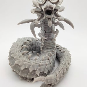 May include: A grey 3D printed model of a monstrous creature with a segmented body, multiple limbs, and a large, gaping mouth.