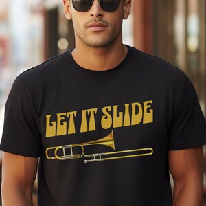 May include: Black t-shirt with the text "LET IT SLIDE" in gold letters and a gold trombone graphic.