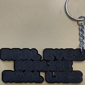 Real Eyes Realize Real Lies - Black acrylic keychain