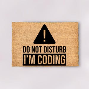 May include: A brown doormat with the text "Do Not Disturb I'm Coding" in black lettering. A black warning sign with an exclamation point is above the text.