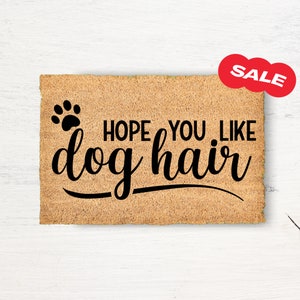 May include: A brown coir doormat with the text "HOPE YOU LIKE dog hair" and a paw print.