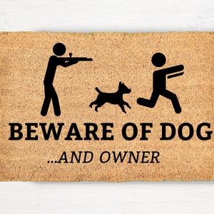 May include: A brown doormat with the text "BEWARE OF DOG...AND OWNER" in black. A stick figure holding a gun is on the left, a stick figure running is on the right, and a dog is in the middle.