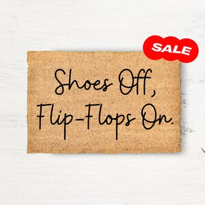 May include: A brown doormat with the text "Shoes Off, Flip-Flops On." A red circle with the word "SALE" is in the upper right corner of the image.