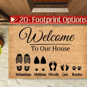 May include: A brown coir doormat with the text "Welcome to Our House" in black cursive font.  Below the text are five footprints, including two boot prints, two bare footprints, and a paw print.  The names "Sebastian", "Melissa", "Nicole", "Leo", and "Rocko" are printed below the footprints.
