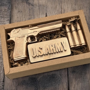 May include: A gold-colored toy gun and three gold-colored bullets in a brown cardboard box with the words "US ARMY" printed on a gold-colored plaque.