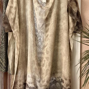 May include: A beige sheer top with a brown snake print design. The top has a scoop neck and short sleeves. The label "GUCCI" is visible on the top.