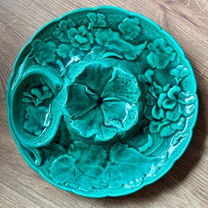 May include: A green ceramic serving dish with a raised floral design. The dish has three sections, one large and two smaller.