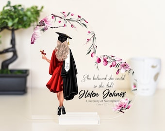 May include: A heart-shaped acrylic plaque with a floral design and a graduate in a red gown and black cap holding a diploma. The text reads "She believed she could so she did! Helen Johnes University of Nottingham Class of 2023".