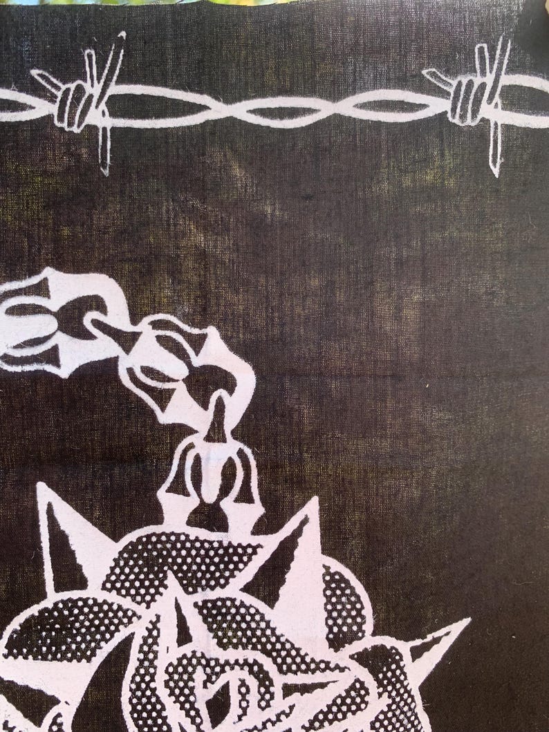 Pode incluir: Um bandana preto com um desenho de arame farpado branco e uma rosa branca com espinhos. A rosa &eacute; estilizada com um padr&atilde;o de pontos.