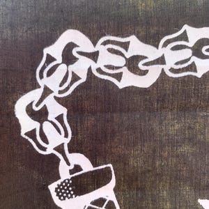 Pode incluir: Uma corrente branca com um isqueiro de metal branco preso a ela. A corrente e o isqueiro est&atilde;o sobre um fundo de tecido marrom escuro.