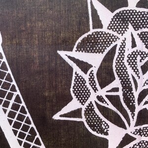 Pode incluir: Um tecido preto com um desenho branco de uma flor estilizada com uma estrela no centro. A flor tem um padr&atilde;o de pontos e &eacute; cercada por pontas afiadas.