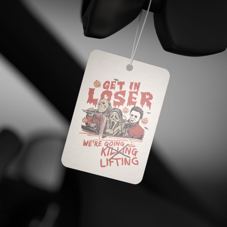 May include: White car air freshener with a red and black illustration of three horror movie characters in a car. The text reads "Get in Loser, We're Going Killing" with a red line through "Killing" and "Lifting" written below.
