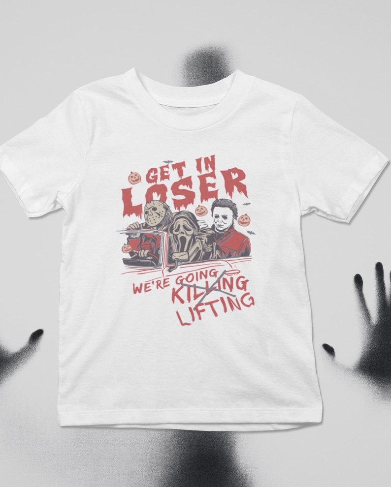 May include: White t-shirt featuring a graphic of three horror movie characters in a car. The text reads "Get in Loser, We're Going Killing Lifting".
