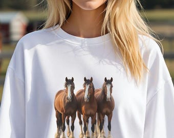 May include: White sweatshirt featuring a graphic of three brown horses with white markings on their faces and legs. The horses are standing side by side. The sweatshirt has a crew neck and long sleeves.
