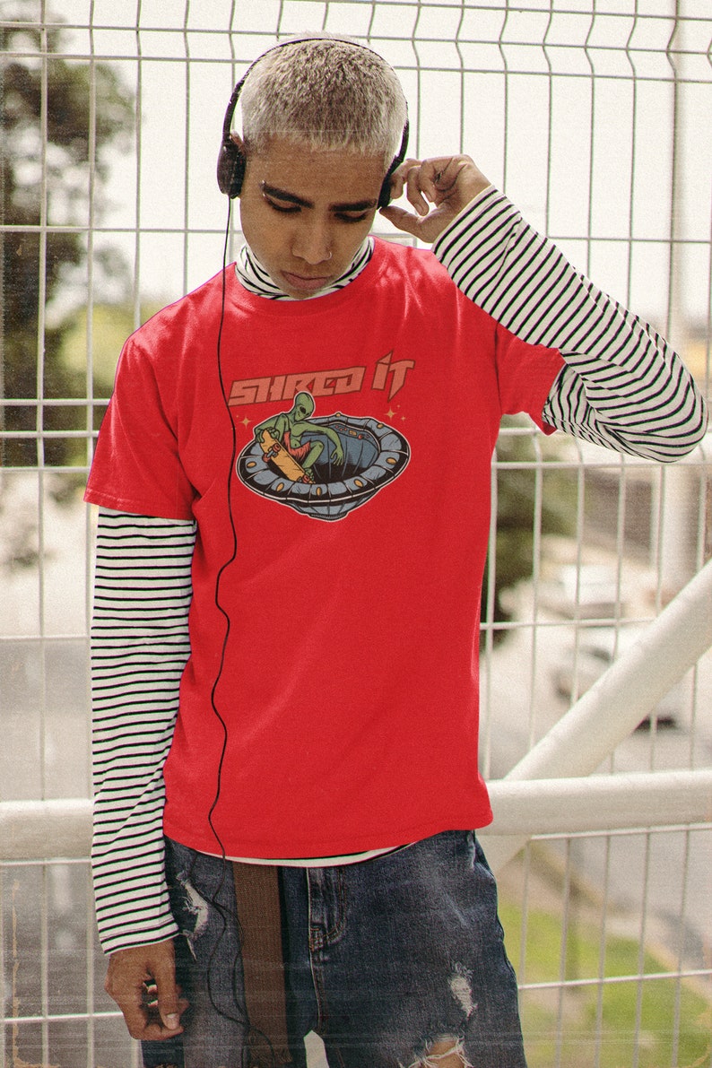 Pode incluir: Uma camiseta vermelha com um gr&aacute;fico de um alien&iacute;gena verde fazendo skate em um disco voador. O texto "Sliced it" est&aacute; impresso na camiseta.