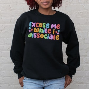 May include: Black sweatshirt with the text "Excuse me while I dissociate" in colourful letters with small flower accents.
