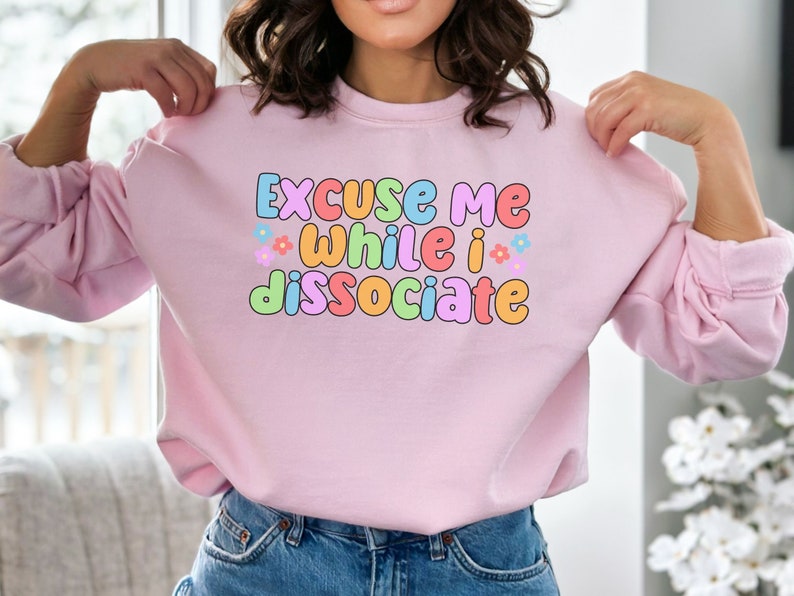 May include: Pink sweatshirt with the text "Excuse me while I dissociate" in colourful letters with small flower accents.