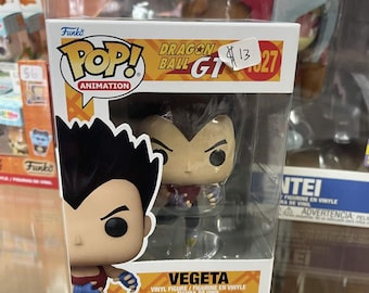 May include: A Funko Pop! Animation figure of Vegeta from Dragon Ball GT. The figure is in a clear plastic display case. The box has the Funko Pop! logo and the text "Dragon Ball GT". The figure is wearing a purple and red outfit.