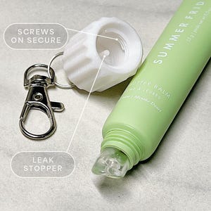 May include: A white plastic bottle stopper with a screw-on lid and a silver keychain. The bottle stopper has a small hole in the center. The keychain has a leak stopper. The text "SCREWS ON SECURE" and "LEAK STOPPER" are written on the image.