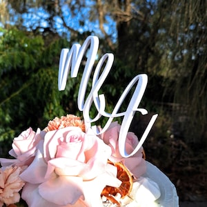 May include: A white cake decorated with pink roses, dried orange slices, and a white topper that says "Mr & Mrs".