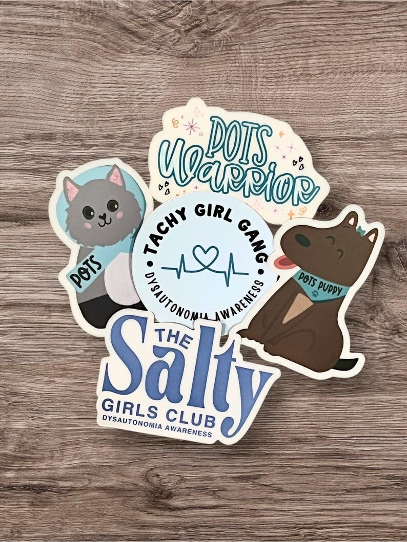 May include: Four stickers with blue and white designs. One sticker features a cat with the text "POTS" and a heart. Another sticker features a dog with the text "POTS PUPPY". A third sticker features a heart with the text "TACHY GIRL GANG" and "DYSAUTONOMIA AWARENESS". The fourth sticker features the text "THE Salty GIRLS CLUB" and "DYSAUTONOMIA AWARENESS".