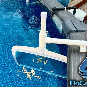 May include: White pool skimmer with a white handle attached to a white pole. The skimmer is in a blue pool and is collecting leaves. The text "FloCatcher" is visible in the lower right corner of the image.