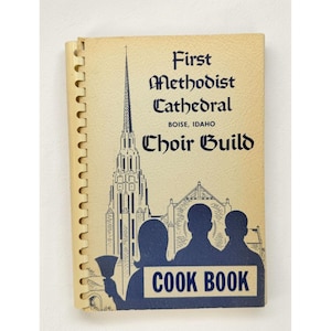 Könnte beinhalten: Vintage Kochbuch mit dem Titel "First Methodist Cathedral Choir Guild Cook Book" mit Spiralbindung. Das cremefarbene Cover zeigt eine blaue Illustration einer Kirche und Silhouetten, mit blauem Text. Das Buch ist cremefarben.