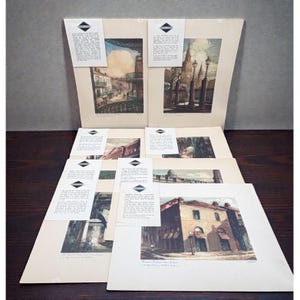 May include: A collection of vintage architectural prints, featuring various cityscapes. Each print showcases detailed illustrations of buildings, bridges, and streets, with accompanying informational cards. The prints are displayed on a dark wooden surface.