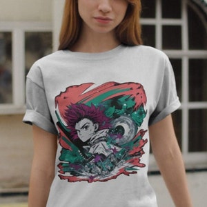 Może przedstawiać: Biała koszulka z kolorowym nadrukiem graficznym postaci anime z czerwonymi włosami i mieczem. Postać otoczona jest zielonymi i czerwonymi wirami.