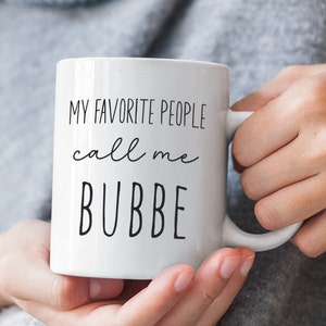 May include: White ceramic mug with black text that reads "My favorite people call me Bubbe".