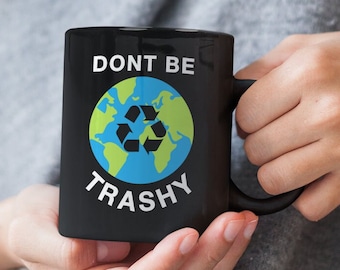 May include: Black ceramic mug with a white graphic of a blue and green earth with a recycle symbol and the text "Don't Be Trashy".