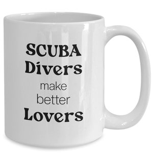 May include: White ceramic mug with the text "SCUBA Divers make better Lovers" in black, bold font. The mug has a curved handle and a glossy finish, perfect for coffee or tea.