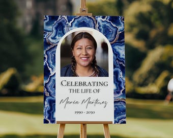 May include: A white memorial sign with a blue agate pattern and a photo of a woman in a white frame. The sign reads "Celebrating the life of Maria Martinez 1990 - 2030".