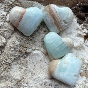 May include: Four heart-shaped blue and brown calcite crystal stones. The stones are smooth and polished, with a natural, organic look.
