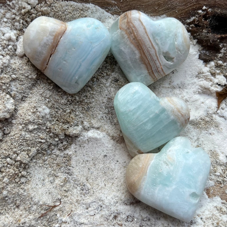 May include: Four heart-shaped blue and brown calcite crystal stones. The stones are smooth and polished, with a natural, organic look.