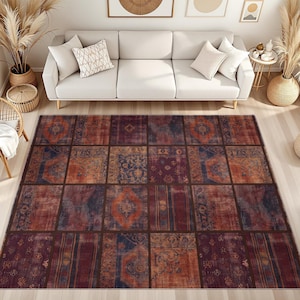 May include: A rectangular area rug featuring a patchwork design composed of various square sections. The rug displays a color palette of deep red, burnt orange, and navy blue, with intricate patterns and faded textures across each individual block.