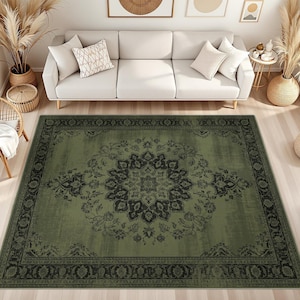 May include: A rectangular area rug featuring a muted olive green base color with a dark charcoal black central medallion and a matching ornate border. The design displays intricate floral and vine motifs throughout the surface of the rug.