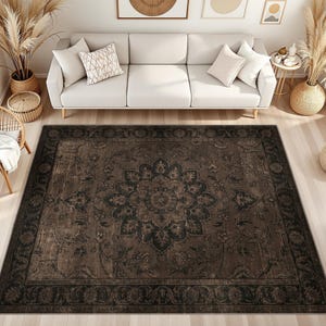 May include: A large, square area rug featuring a dark brown and black color palette with a central floral medallion motif and an intricate, ornate border pattern. The rug has a distressed, weathered appearance with visible vintage-inspired detailing.