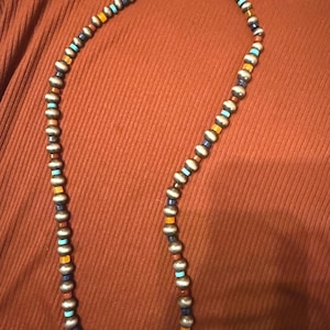 May include: A silver beaded necklace with alternating sections of silver beads and colorful accent beads in turquoise, orange, and navy blue. The necklace has a silver clasp.