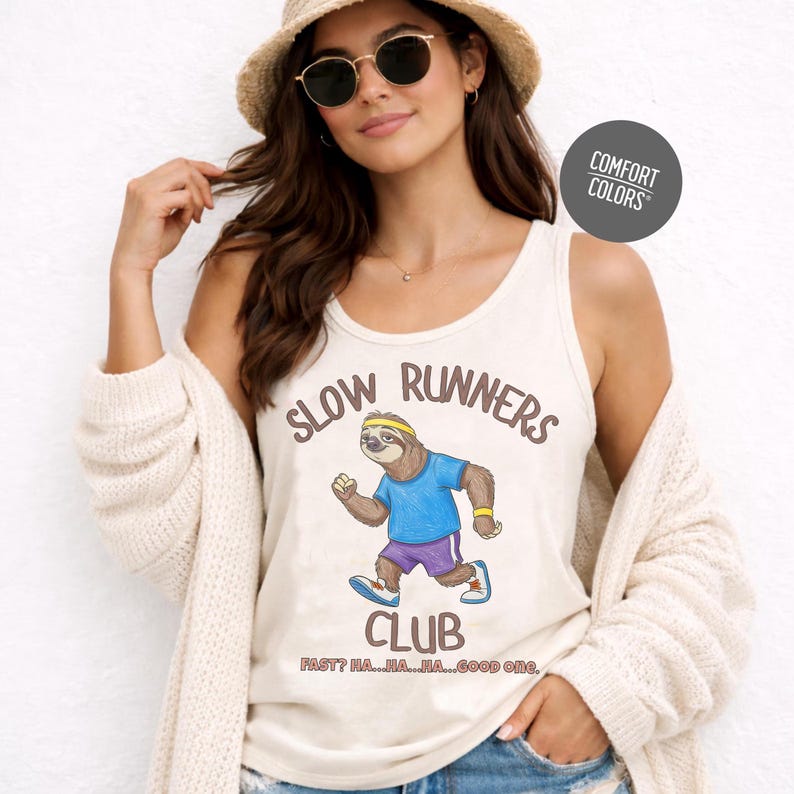 May include: Cream-colored tank top with the words "SLOW RUNNERS CLUB" and a cartoon sloth running. The sloth wears a blue shirt, purple shorts, and a yellow headband. The text "FAST? HA...HA...HA...GOOD ONE." is below the sloth.