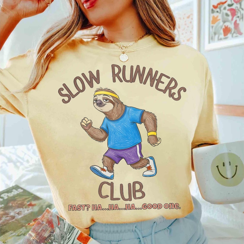 May include: Yellow t-shirt with the text "SLOW RUNNERS CLUB" and a cartoon sloth wearing a headband, blue shirt, and purple shorts. The text "FAST? HA...HA...HA...GOOD one." is below the club name.