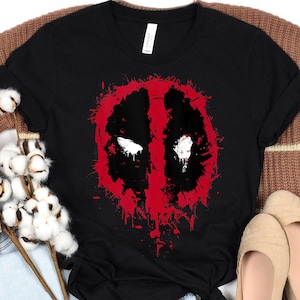 Camiseta Marvel Deadpool com estampa de respingos de tinta, ideal para festas em família da Marvel em 2026, camiseta para fãs do MCU, camiseta da Marvel Comics 2026 e camiseta para viagem à Disneylândia.