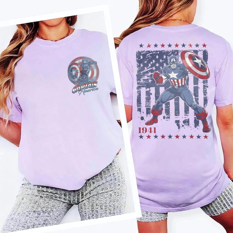 May include: A light purple t-shirt featuring a small Captain America graphic on the front left chest. The back displays a large graphic of Captain America holding a shield in front of a distressed American flag, with the text 1941 and rows of stars.