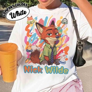 May include: White t-shirt with a cartoon fox character, Nick Wilde, in a green shirt and tie, set against a colourful abstract background. The shirt has the text "Nick Wilde" in blue and yellow. The shirt also has the text "Comfort Colors White".