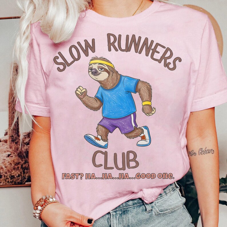 May include: A light pink t-shirt with the words "SLOW RUNNERS CLUB" in brown lettering. A cartoon sloth wearing a blue shirt and purple shorts is running. The text "FAST? HA...HA...HA...GOOD ONE." is below the sloth.