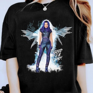 Op de afbeelding: Zwart T-shirt met een afbeelding van een personage in een paarse en zwarte outfit met de tekst "GOOD 2B BAD!". Het personage staat voor een gestileerde blauw-witte achtergrond.