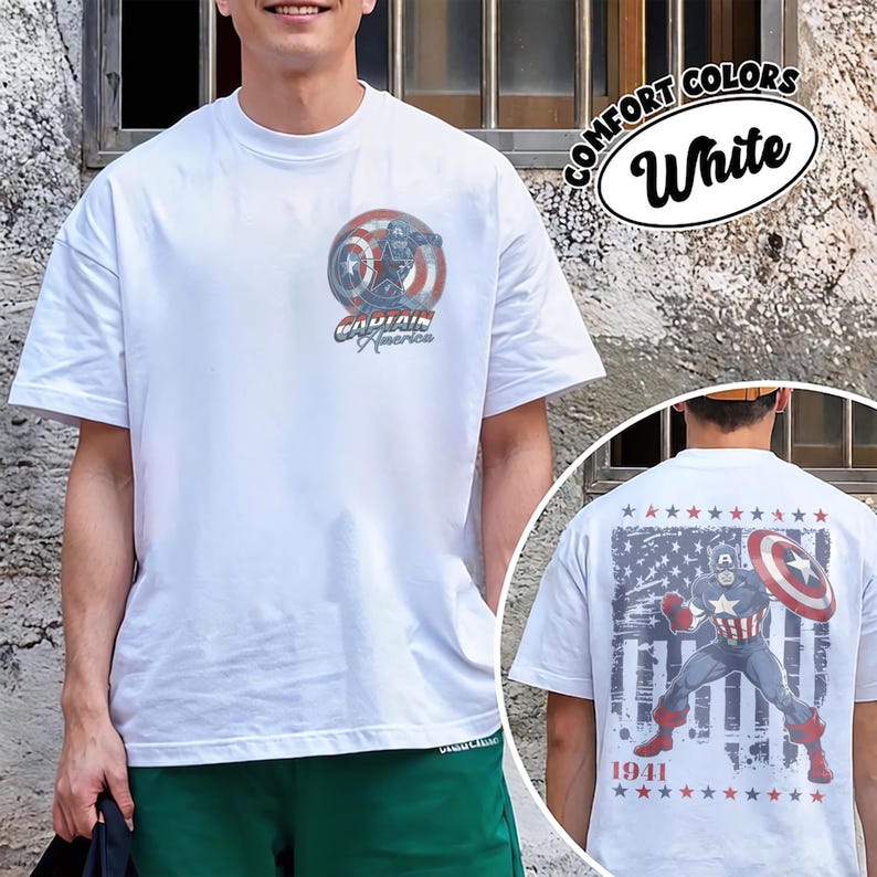 May include: A white short-sleeve t-shirt featuring a small Captain America shield graphic on the left chest and a large graphic on the back depicting Captain America with a shield against a distressed American flag background and the text 1941.