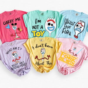 May include: Six brightly coloured t-shirts featuring a cartoon fork character and phrases such as "Carry Me" and "What the Fork." The shirts are in pink, light blue, yellow, lavender, and light pink.